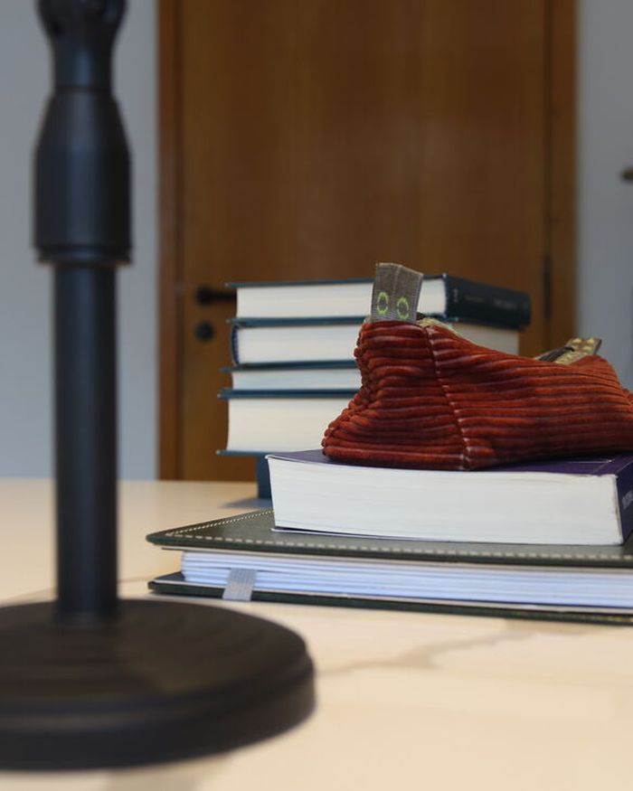 Livros empilhados e um estojo de veludo vermelho sobre a mesa de mármore do consultório